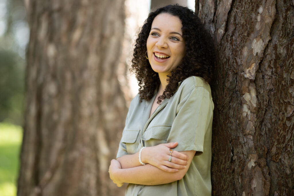 Image of the new poet in residence, leaning against a tree and smiling