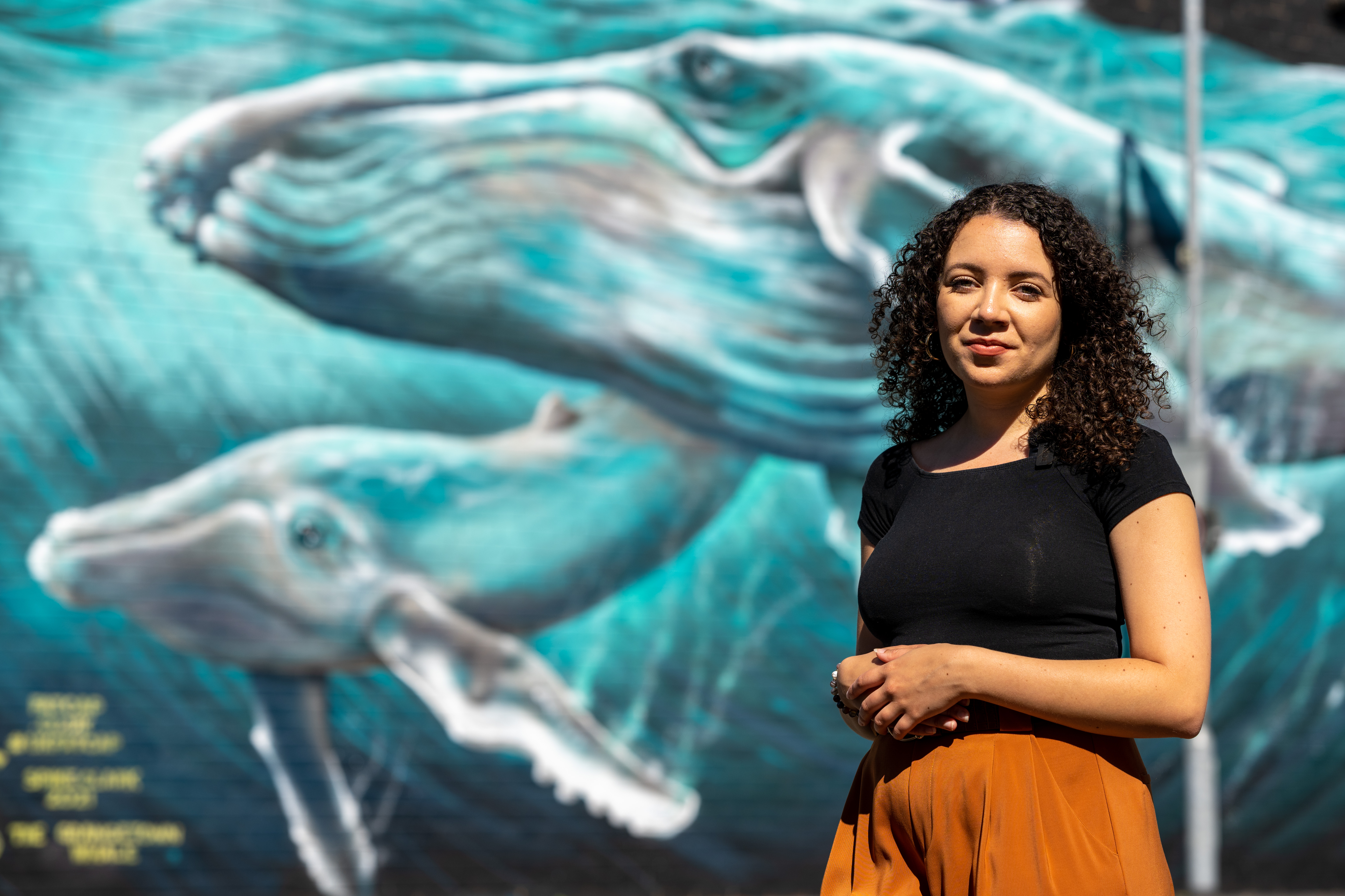 Our Poet in Residence Taylor Edmonds standing in front of a giant whale mural in Cardiff which highlights global warming and rising sea levels.
